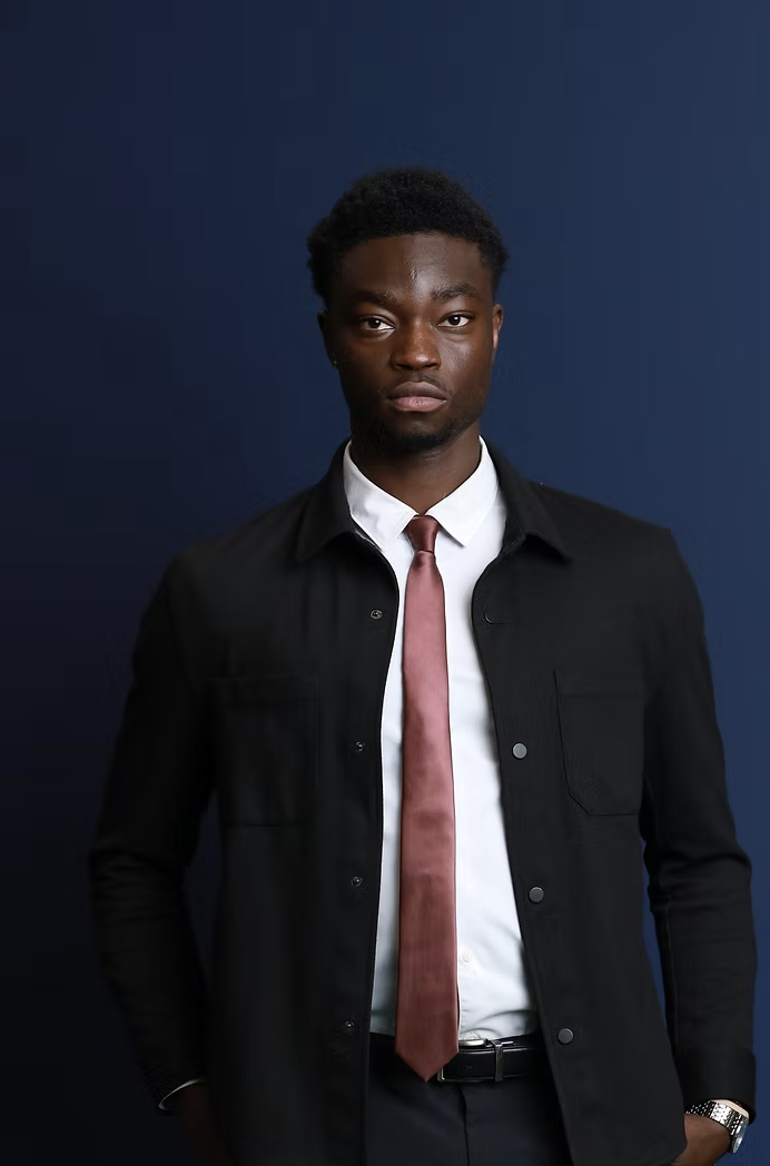 Jaeschel Acheampong wearing a suit and tie against a blue backdrop